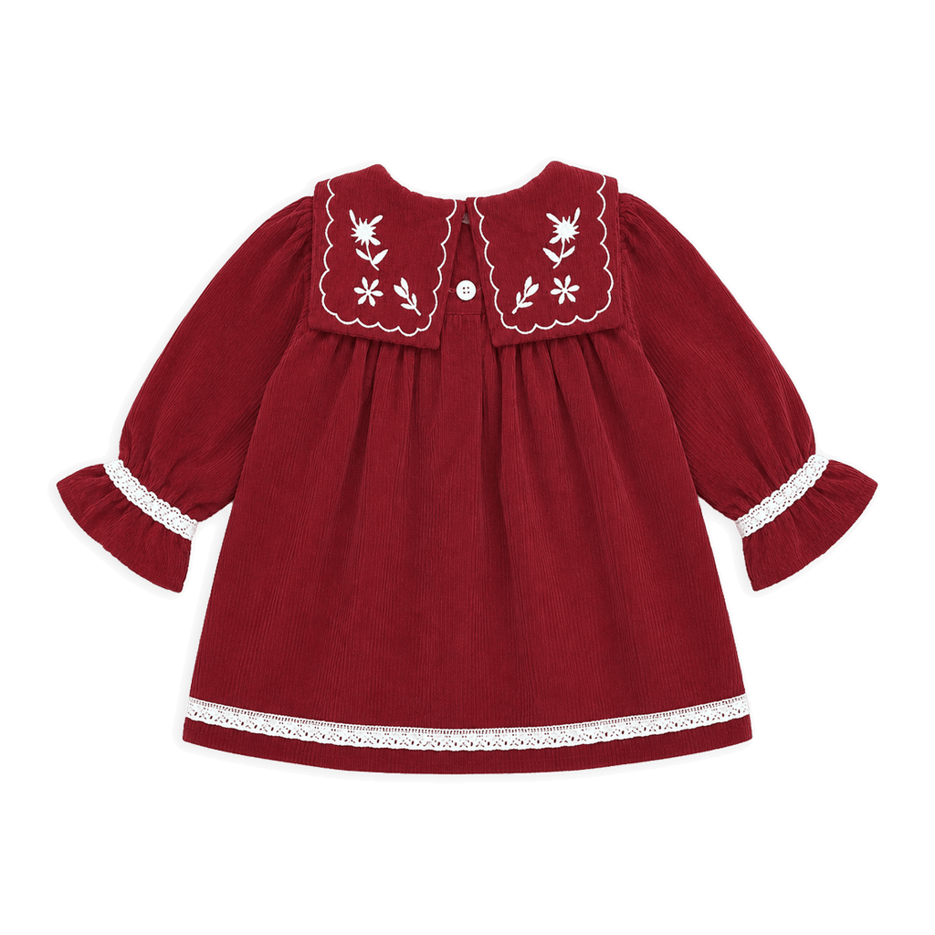A red long-sleeve baby dress with white embroidered floral details on the collar, white lace trim on the cuffs and hem, and a small white button at the back neckline, shown against a solid black background.