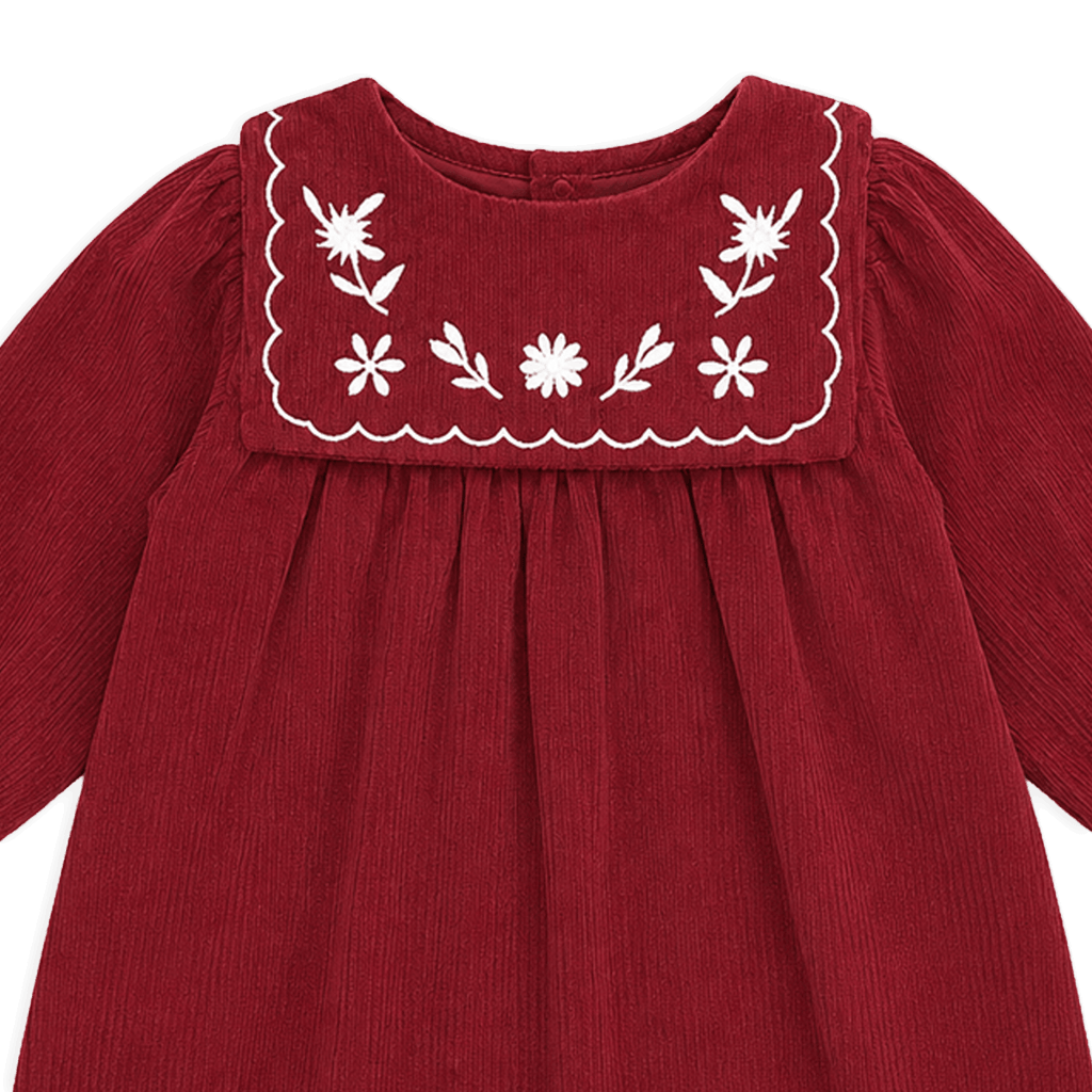 Red dress with white floral embroidery on a black background
