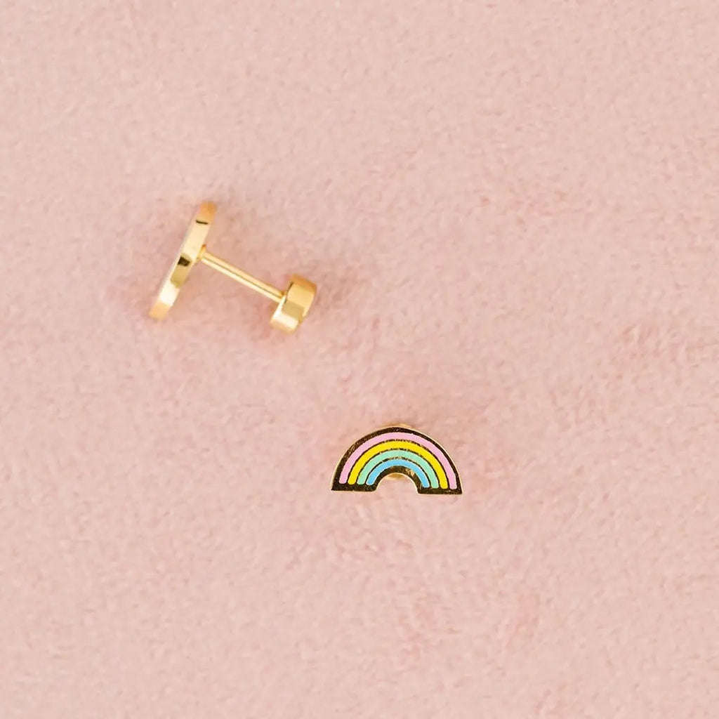 Gold rainbow-shaped earring on a pink background