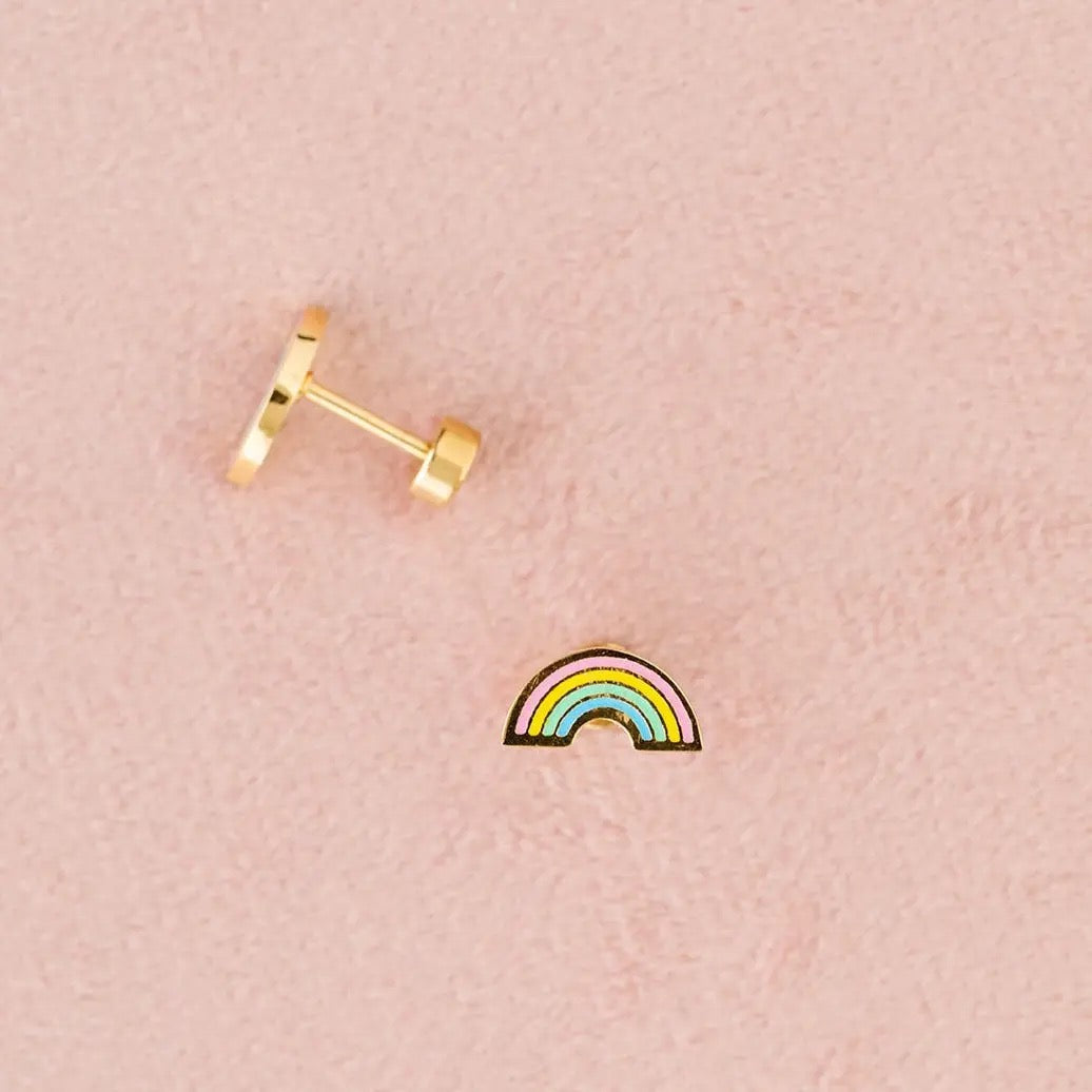 Gold rainbow-shaped earring on a pink background