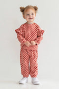 Child wearing a red polka dot outfit on a white background