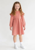 Young girl wearing a red polka dot dress on a white background