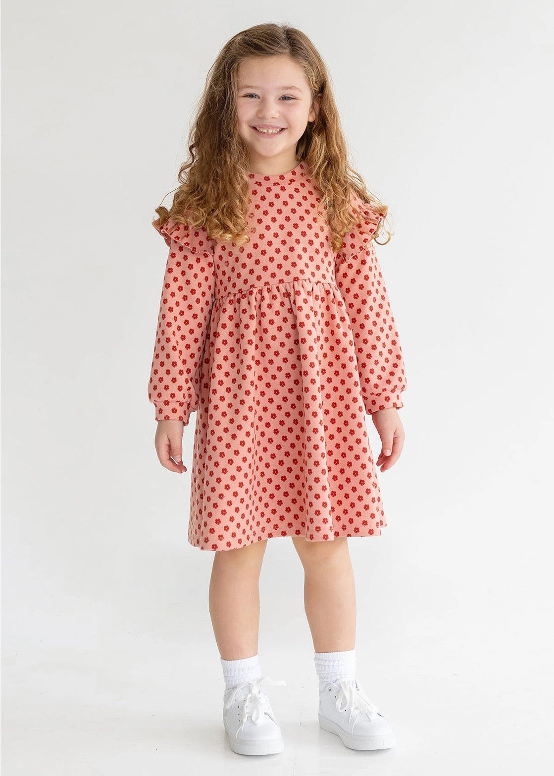 Young girl wearing a red polka dot dress on a white background