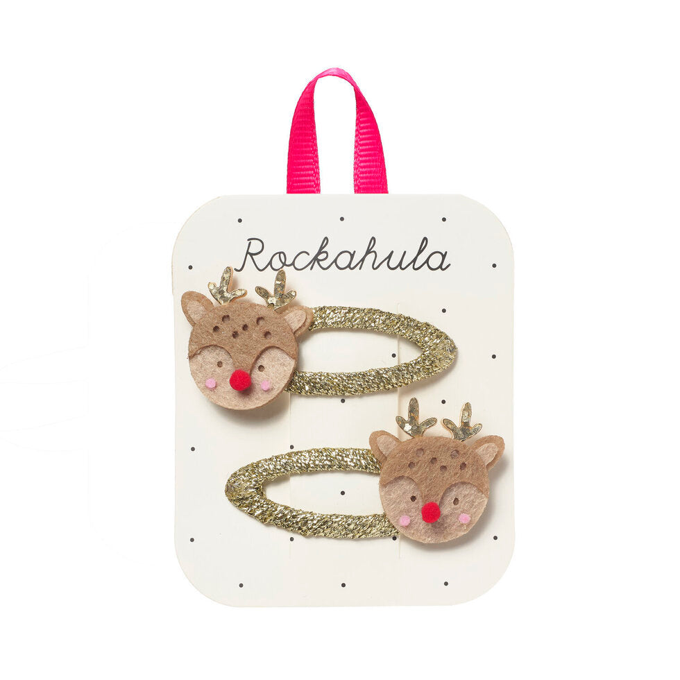 Two hair clips with reindeer faces and glittery gold bands, attached to a white display card with a pink ribbon loop, labeled 'Rockahula'.