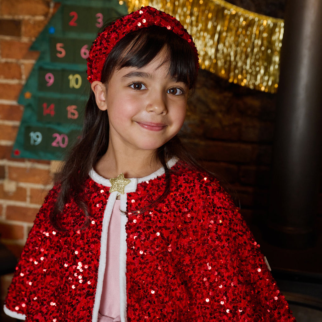young girl wearing red sequin headband and cape